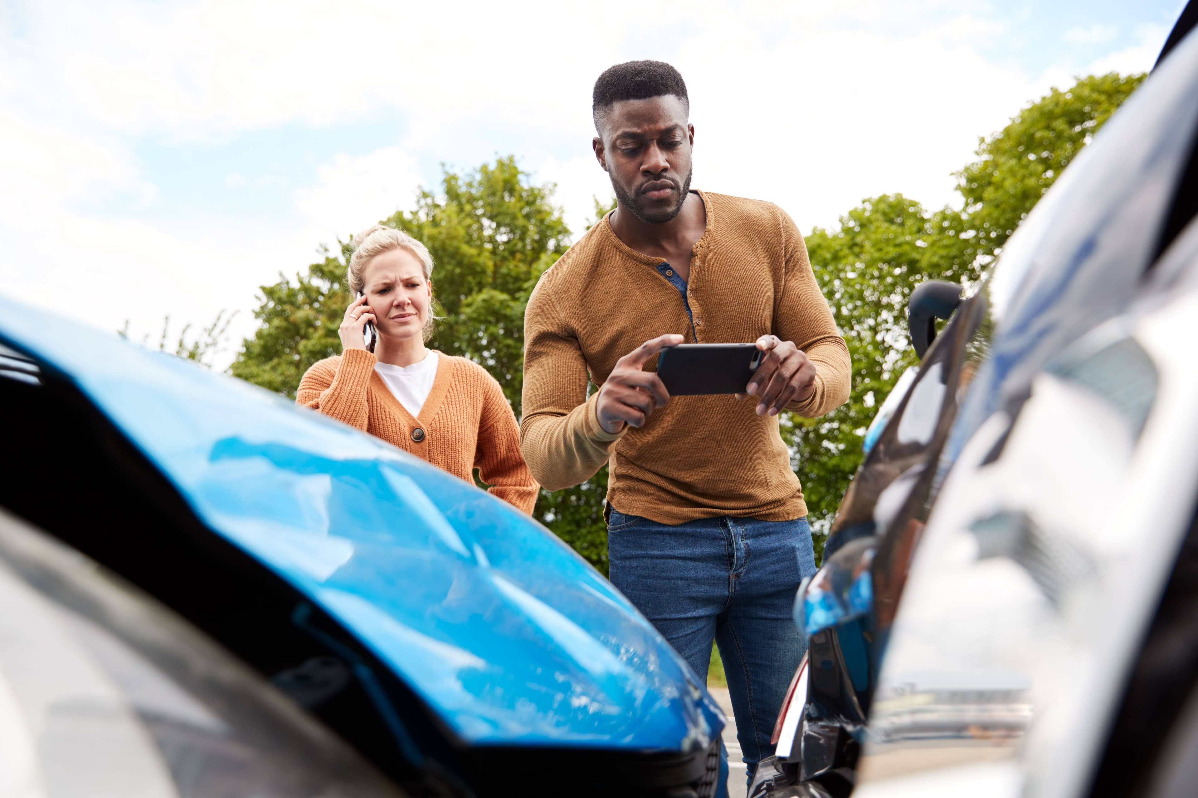 Two drivers following critical steps on an accident checklist by calling the authorities and documenting the scene.