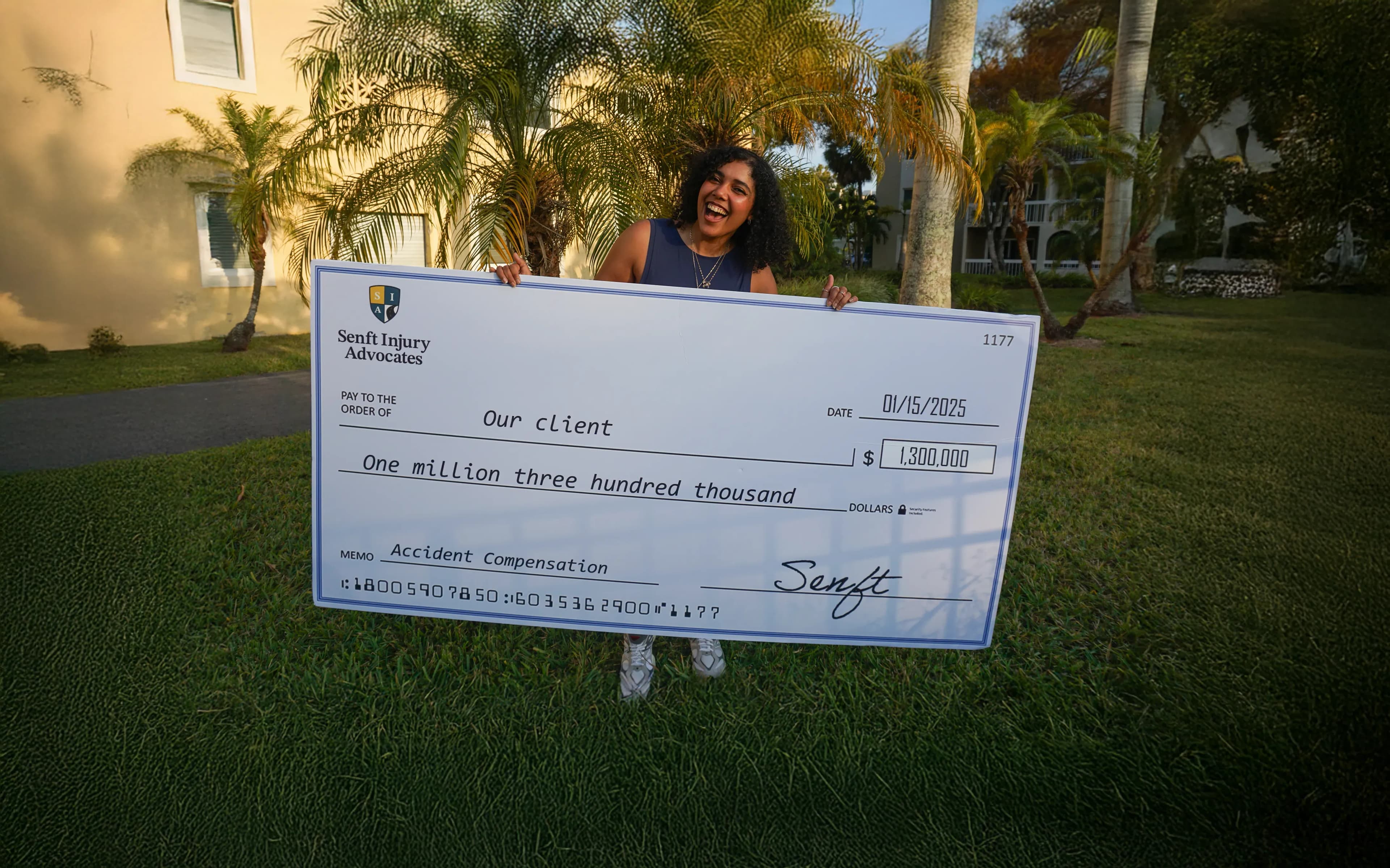 Client holding large check from her injury case settlement of one million three hundred thousand dollars.